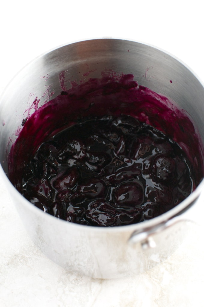 Deep purple berry compote in stainless steel saucepan for dessert topping or baking ingredients.