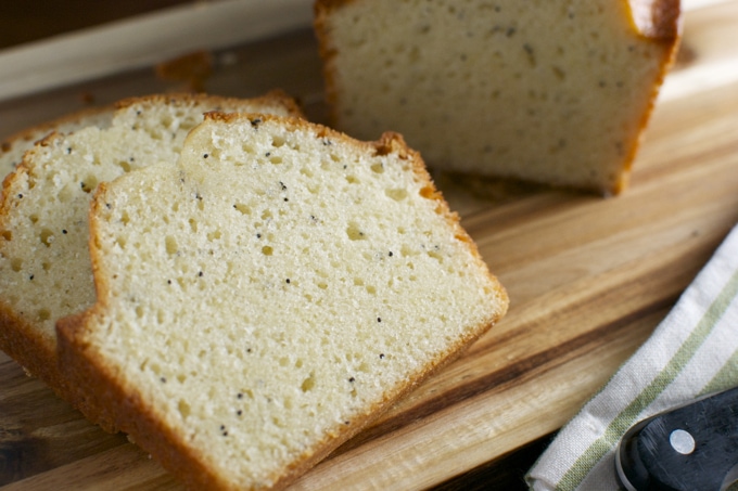 Fluffy homemade vanilla bean pound cake slices on wooden cutting board, perfect for dessert or teatime.
