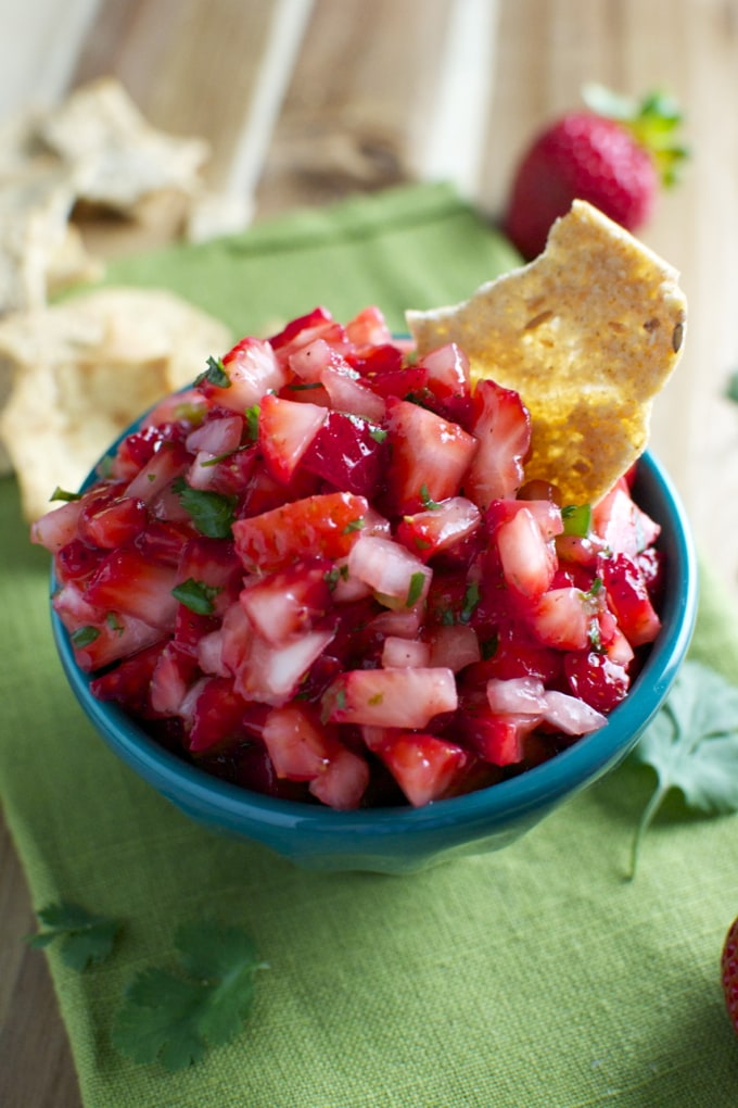 Fresh strawberry fruit salad in a blue bowl, topped with a crispy tortilla chip, perfect for summer desserts or healthy snacks.
