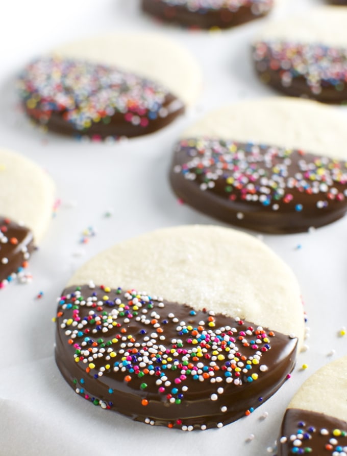 Buttery half-dipped sugar cookies with colorful rainbow sprinkles, perfect for sweet treats and dessert recipes, appealing for celebrations and festive occasions.