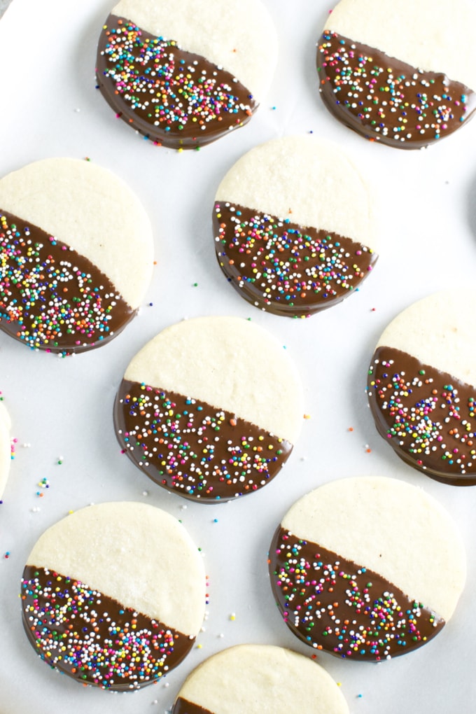Colorful half-dipped cookies with chocolate coating and sprinkles, perfect for sweet treats and dessert tables.