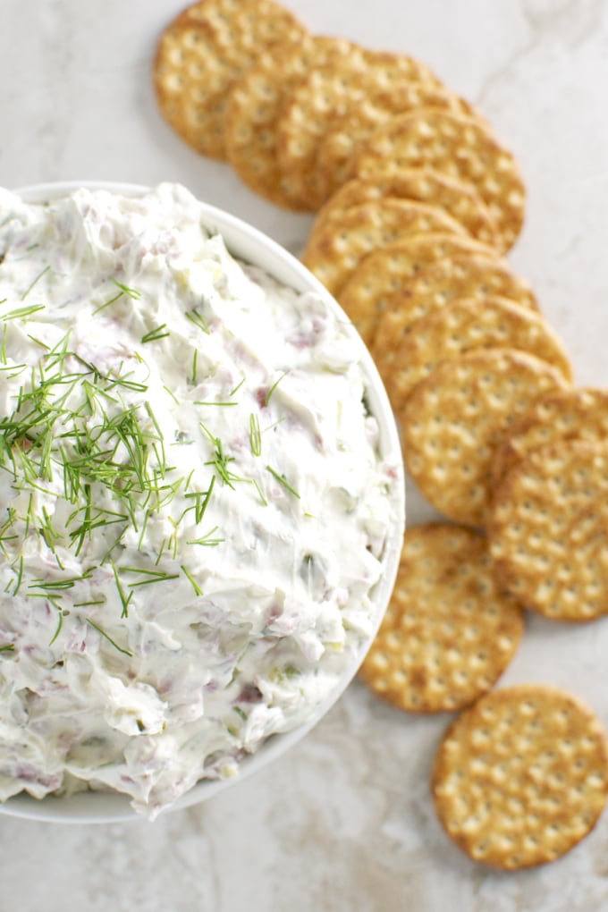 Creamy vegetable dip with fresh herbs served with crispy crackers, perfect for parties and appetizers.