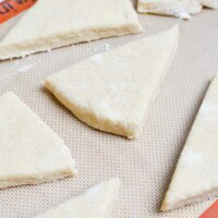 Flaky homemade puff pastry dough triangles on a baking mat, ready for baking or filling, perfect for sweet or savory recipes.