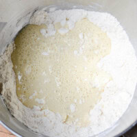 Flour and wet ingredients in mixing bowl for baking recipe.