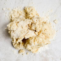 Crumbly uncooked pie crust dough on a light surface for baking.