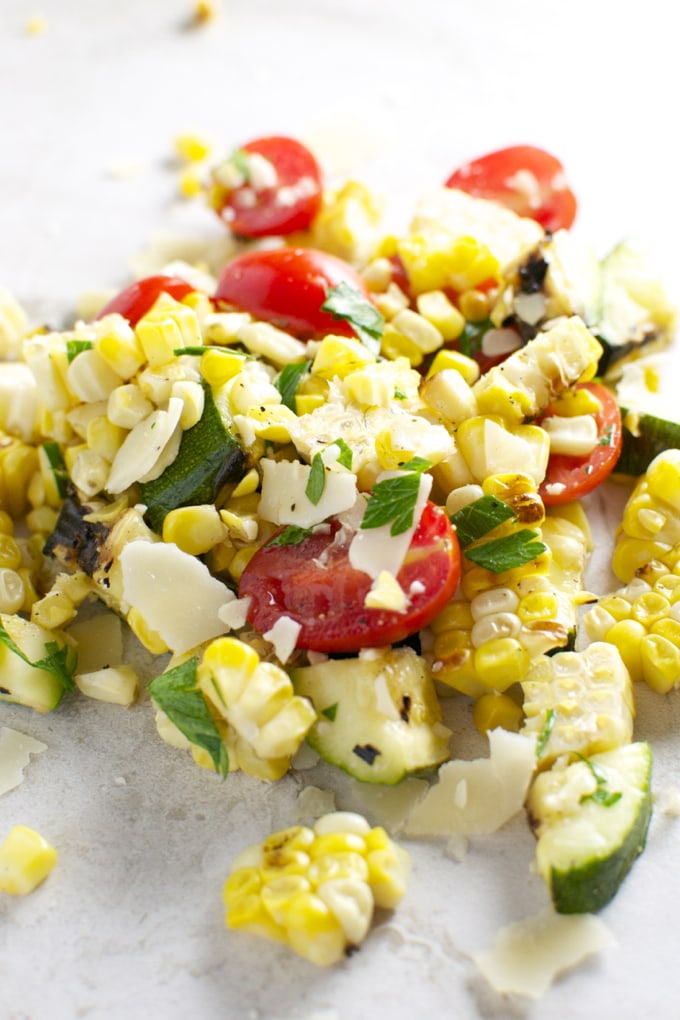 Fresh roasted vegetable salad with cherry tomatoes, corn, zucchini, and cheese, served with herbs—perfect for healthy eating and summer meals.