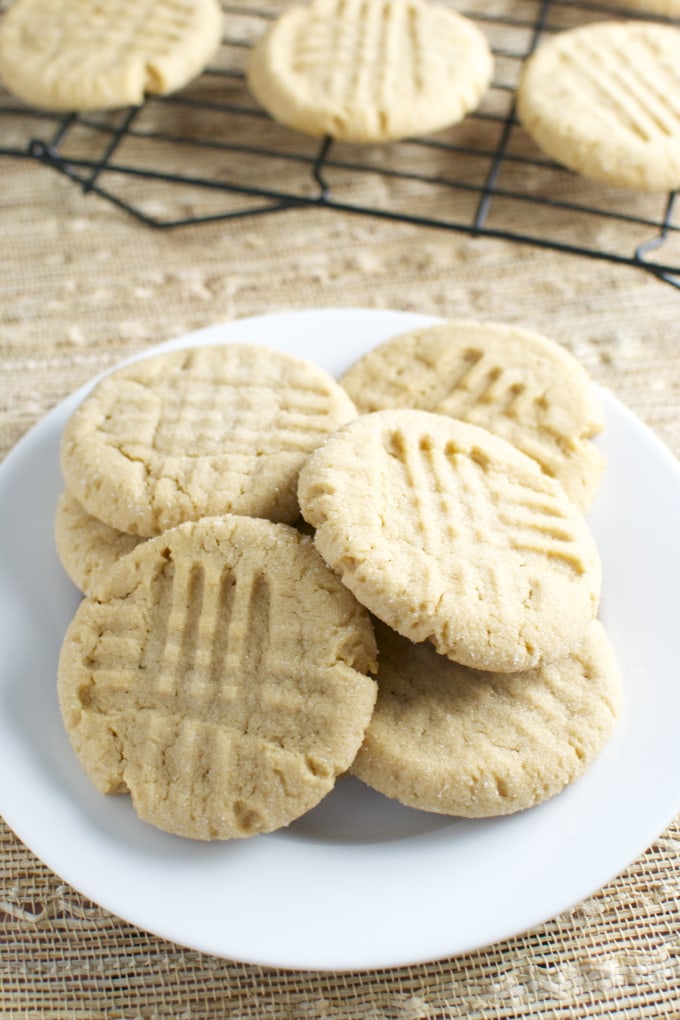 Butter cookies on a white plate with a wooden table background, fresh baked, classic homemade cookies, sweet treats, baked goods, no added sugar, vanilla flavor.