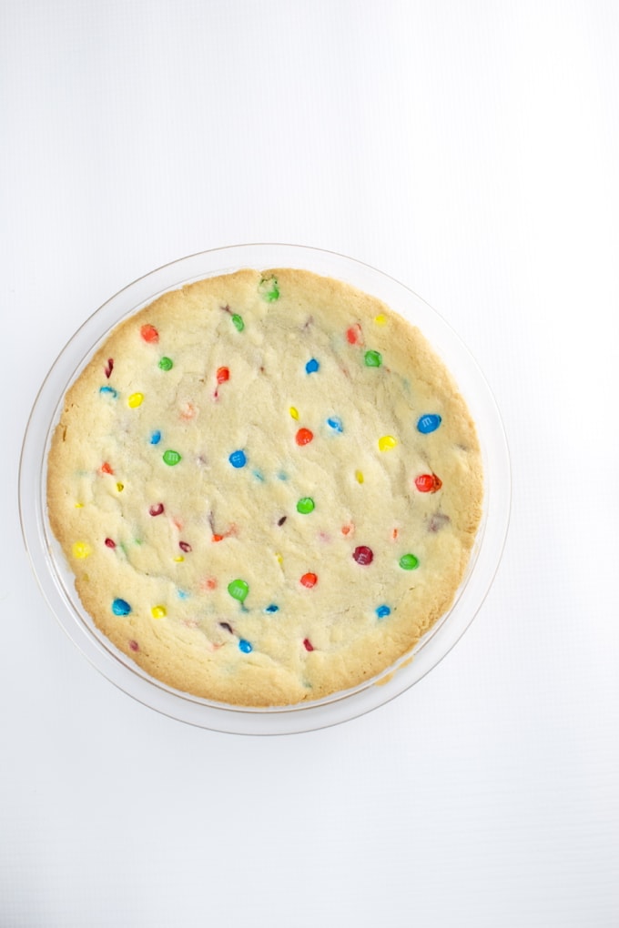 Soft sugar cookie with colorful M&M candies on a white background, perfect for sweet treats and dessert lovers.