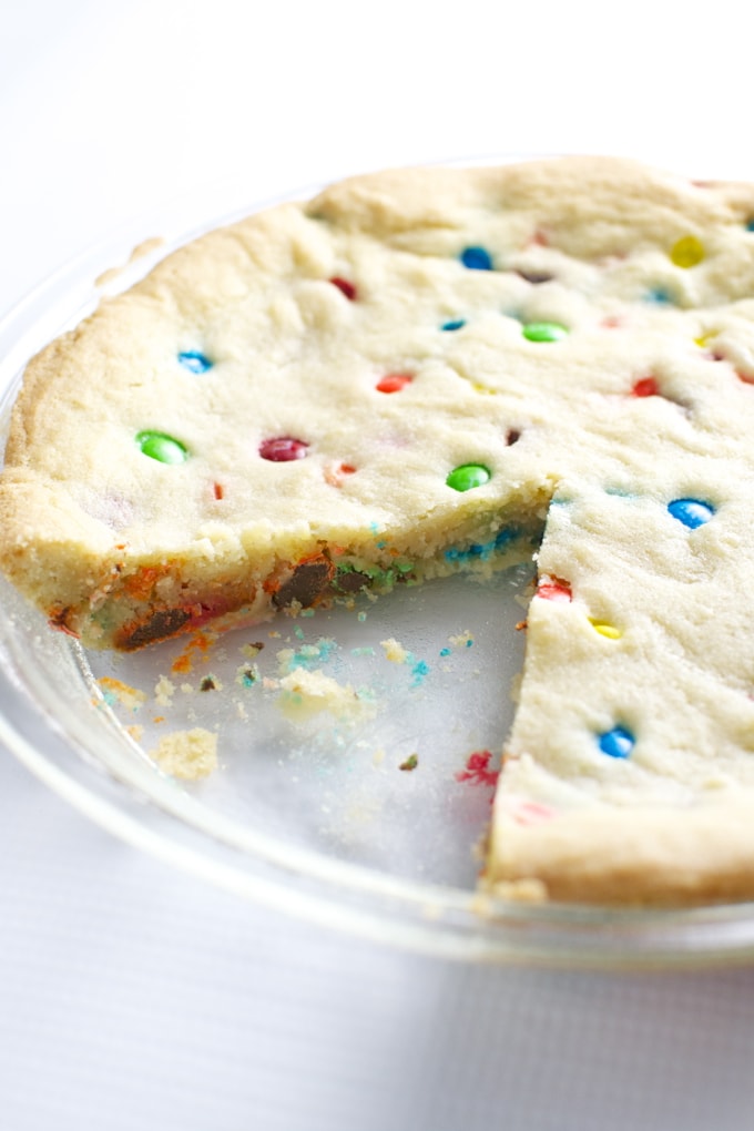 Colorful candy cookie with rainbow sprinkles and a bite taken out, perfect for dessert or special occasions.