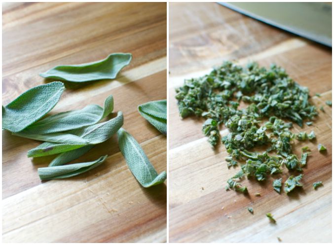 Fresh sage leaves and chopped sage on a wooden cutting board, highlighting herbal ingredients for cooking.