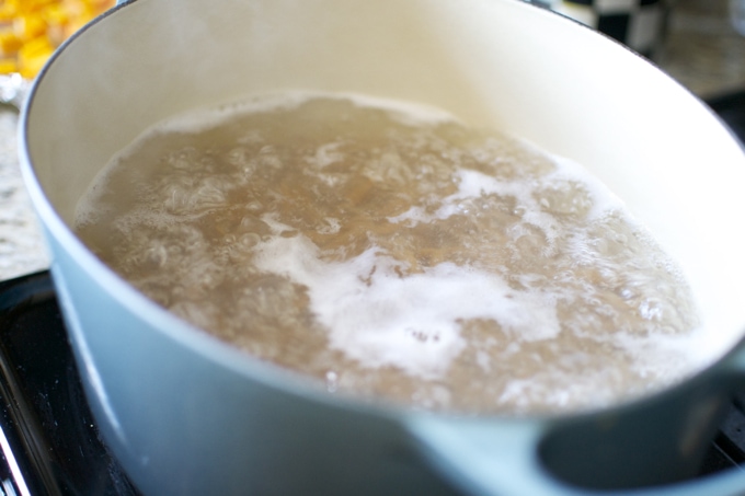 Boiling water in a light blue saucepan on a stove, ready for cooking or baking, over a wooden countertop.