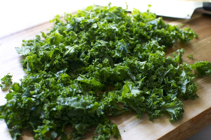 Fresh kale leaves on a wooden cutting board for healthy recipes and smoothies.