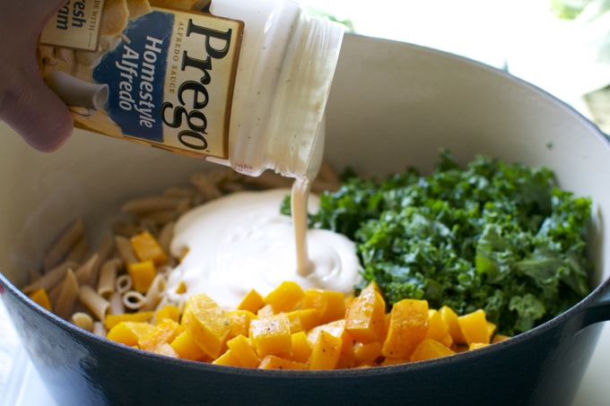 Creamy salad dressing being poured over fresh chopped vegetables in a large bowl.