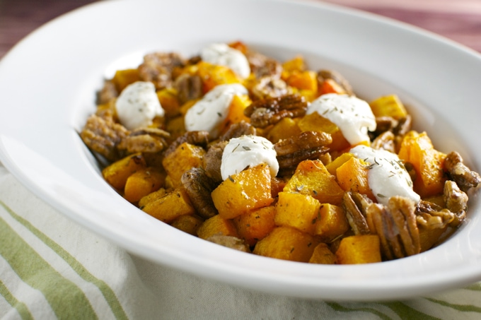 Savory breakfast hash with roasted sweet potatoes, ground sausage, and dollops of sour cream served in a white bowl.
