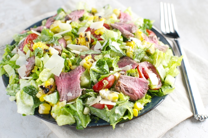 Grilled steak salad with fresh vegetables and corn on a black plate, healthy and colorful meal for summer or lunch.