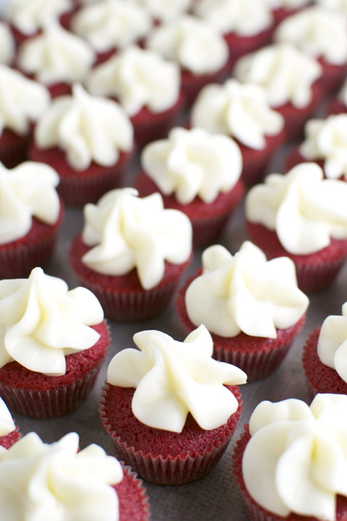 Bright red velvet cupcakes with smooth white frosting, perfect for dessert and party treats on Stuck On Sweet website.