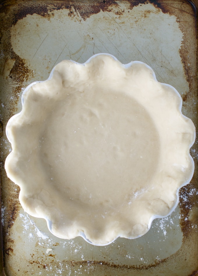 Freshly prepared pie crust in a scalloped baking dish ready for baking at Stuck On Sweet.