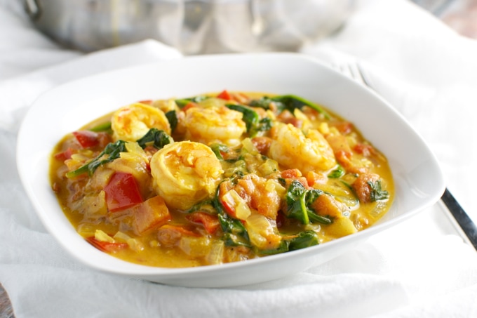 Creamy shrimp and vegetable soup with vibrant bell peppers and spinach in a white bowl. Perfect comfort food filled with fresh ingredients and rich flavors.