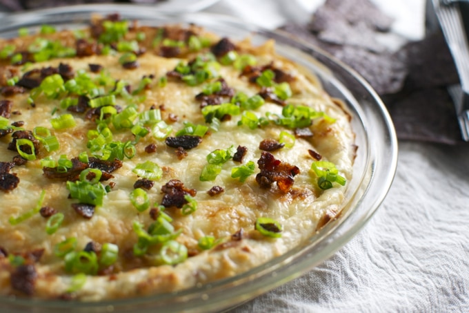 Creamy baked potato casserole topped with green onions and bacon bits, served in a glass baking dish. Perfect comfort food for family dinners or holiday gatherings.