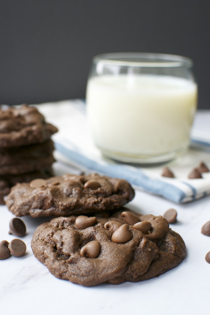 Chocolate chip cookies with a glass of milk on a white surface, showcasing a sweet treat from Stuck On Sweet. Perfect for dessert, snacks, or satisfying a chocolate craving.