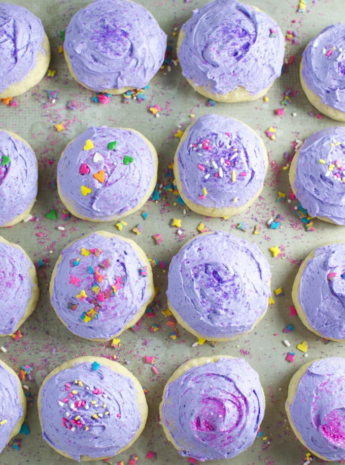 Lavender whipped cookies with colorful sprinkles on a pastel green surface, perfect for sweet tooth cravings and festive celebrations.