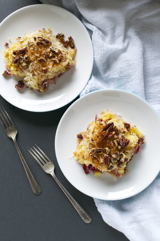 Rich and cheesy cherry cobbler dessert topped with toasted pecans on white plates - perfect for comfort food lovers.