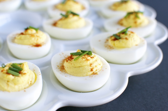 Creamy deviled eggs garnished with chives on a white platter, perfect for appetizers or party snacks. Classic, delicious, and easy to prepare.
