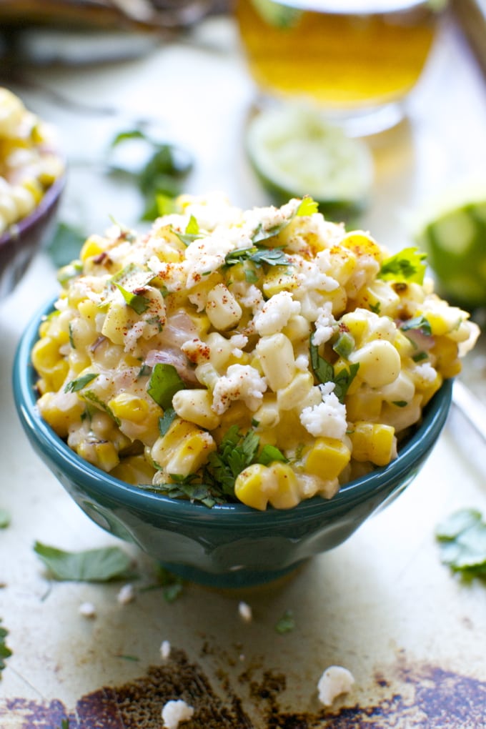 Creamy Mexican street corn salad with fresh cilantro, lime juice, and cotija cheese in a turquoise bowl. Perfect for summer parties and barbecues.