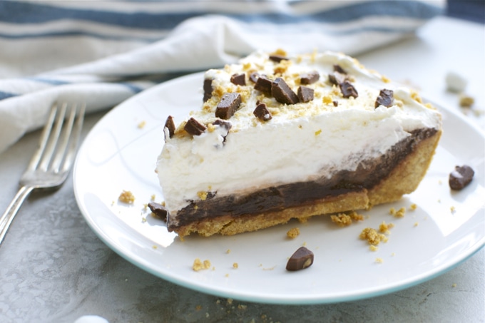 Creamy no-bake chocolate layered cheesecake with a graham cracker crust and whipped topping, topped with chocolate chunks and sweet golden graham cracker crumbs. Perfect for dessert lovers.