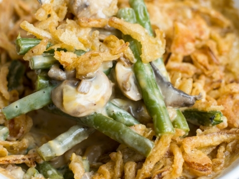 Creamy mushroom and green bean casserole topped with crispy fried onions in a white baking dish, perfect for comforting family dinners and holiday celebrations.