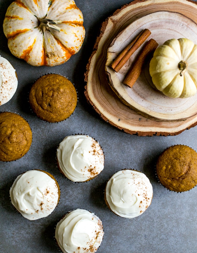Pumpkin muffins with cream cheese frosting and cinnamon sticks on a rustic wooden slab, autumn bakery treats, seasonal pumpkin desserts, fall baking, Stuck On Sweet.