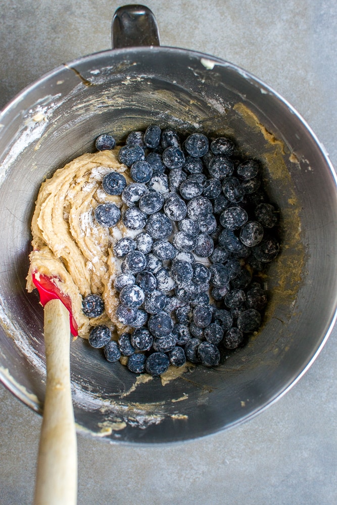 Fresh blueberry muffin batter mixed with blueberries in a mixing bowl, ready for baking.