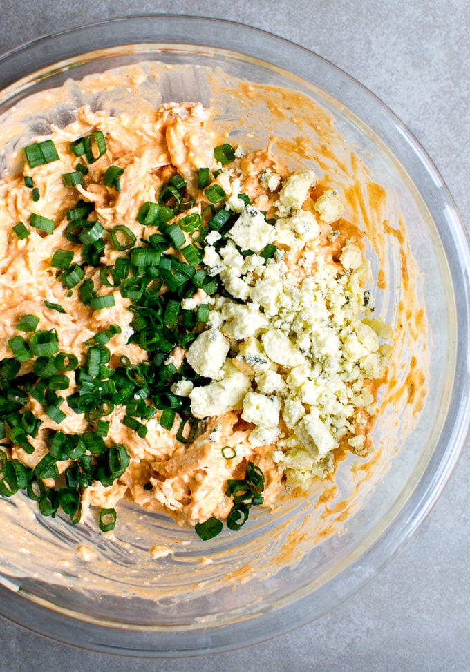 Cream cheese mixture with green onions and blue cheese crumbles for a flavorful buffalo chicken dip. Perfect for parties and gatherings, easy to prepare and always a hit.