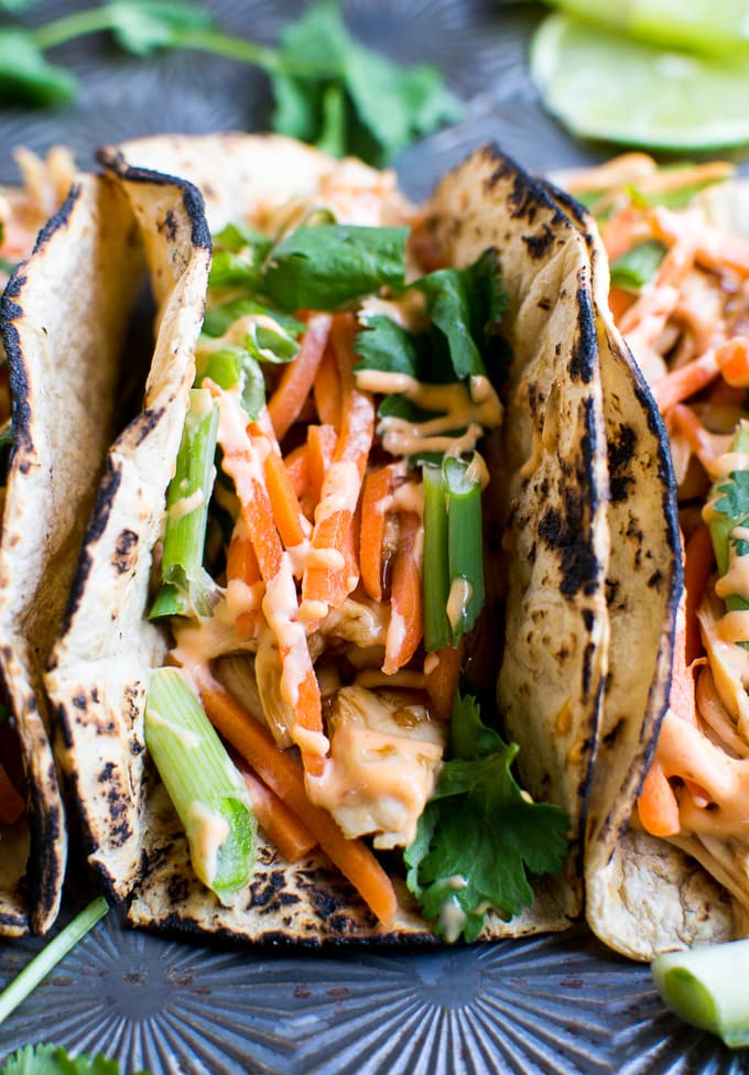 Grilled chicken tacos with fresh vegetables, lettuce, and creamy sauce on a dark plate, showcasing a delicious and healthy Mexican-inspired meal. Perfect for quick dinner ideas.