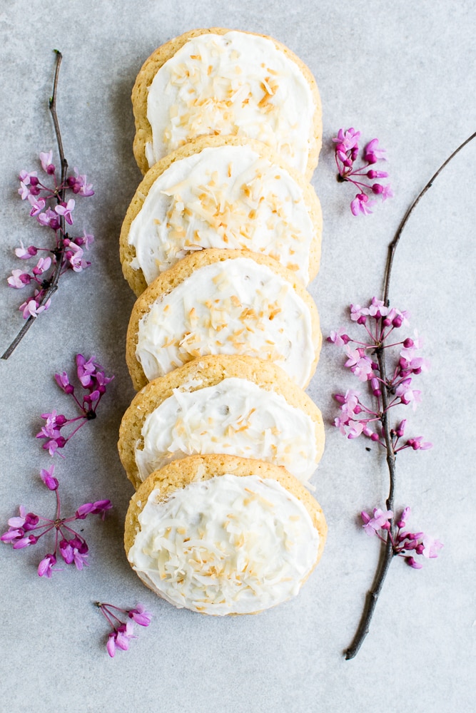 Buttercream coconut cookies on a grey background with pink flowers.