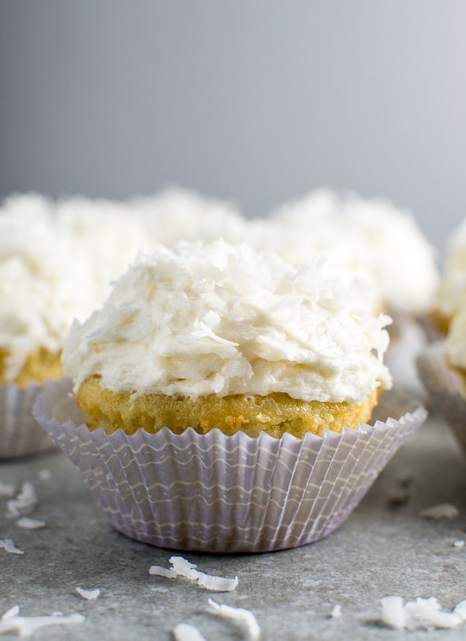 Fluffy coconut cupcake with creamy frosting on a textured surface, perfect for desserts and sweet treats.