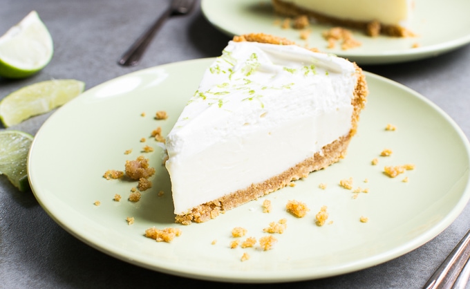 Creamy key lime cheesecake with a graham cracker crust on a pastel green plate, garnished with lime slices, perfect for dessert lovers and sweet treats from Stuck On Sweet.
