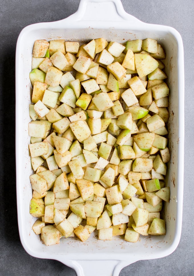 Diced Granny Smith apples seasoned with cinnamon in a white baking dish for baking or apple desserts.