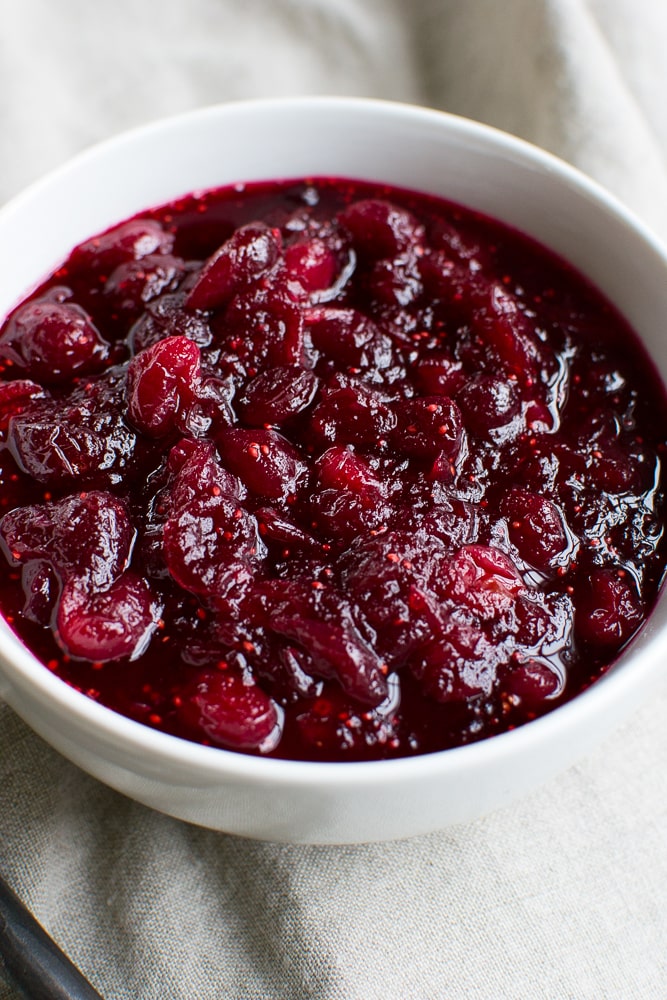 Homemade cranberry sauce in a white bowl, perfect for desserts or breakfast toppings.