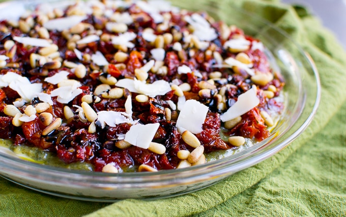 Sweet cherry topping with toasted coconut and pine nuts in a glass dish on a green cloth, ideal for desserts and baking recipes.