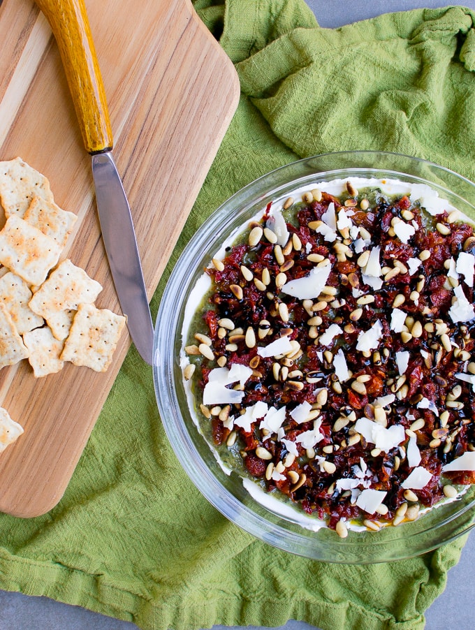 Delicious cranberry white chocolate almond shortbread bars on a green cloth with crackers and a knife, perfect for holiday baking and dessert recipes.