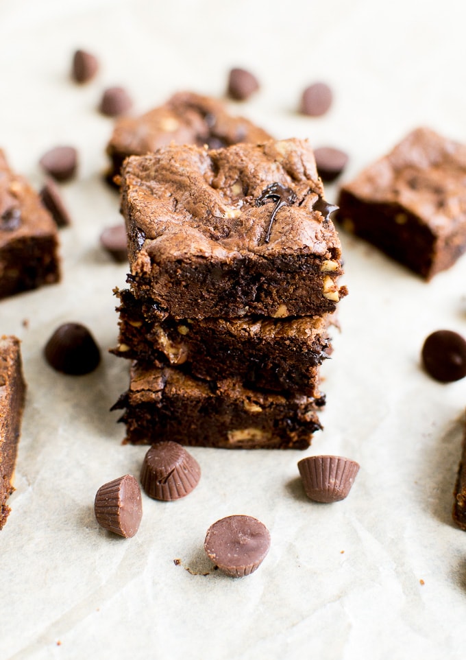 Rich chocolate brownie chunks with mini chocolate chips, on parchment paper backdrop, close-up image.