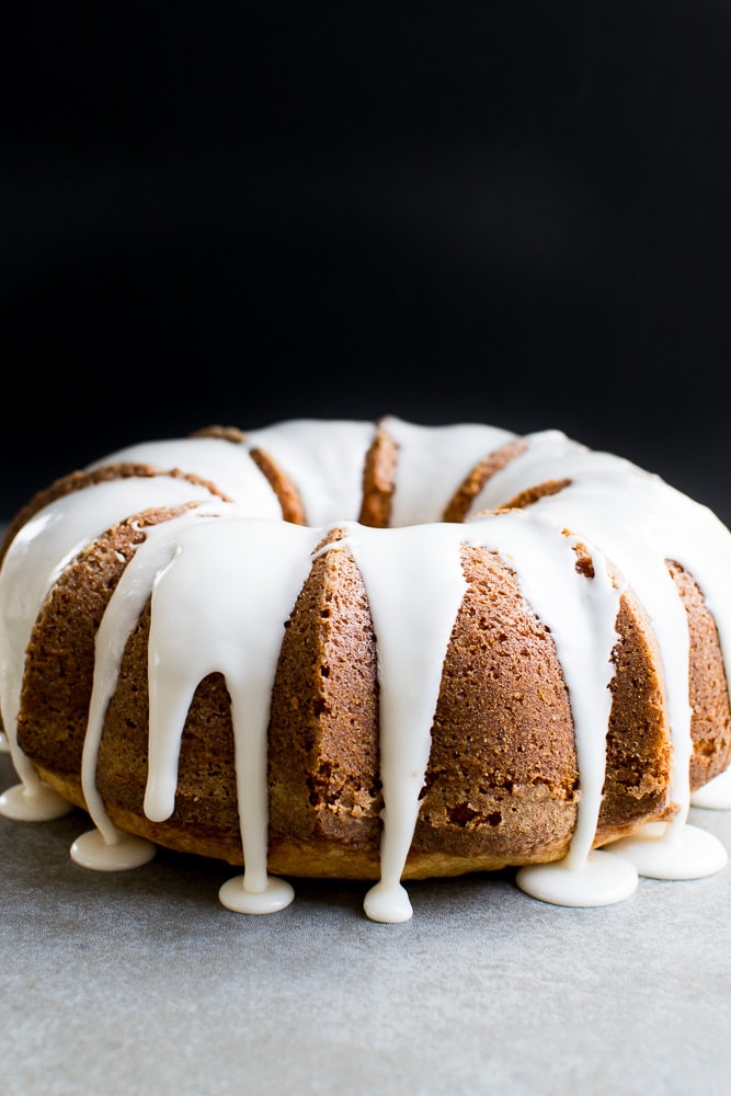 Moist chocolate bundt cake with white icing drizzle, on a neutral surface against a black background. Perfect for dessert or special occasions, showcasing rich, decadent flavors.