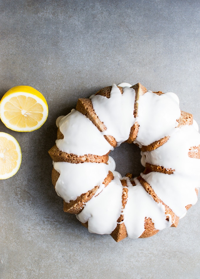 Lemon shortbread cookie wreath with white icing, on gray background with lemon slices.