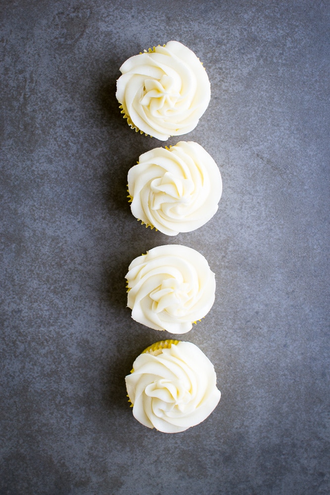 Cream cheese frosting cupcakes on grey background.