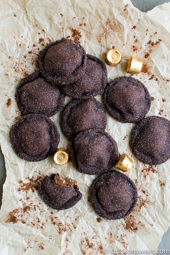 Rich chocolate crinkle cookies on parchment paper with cocoa powder and gold foil chocolates for decadent dessert inspiration.