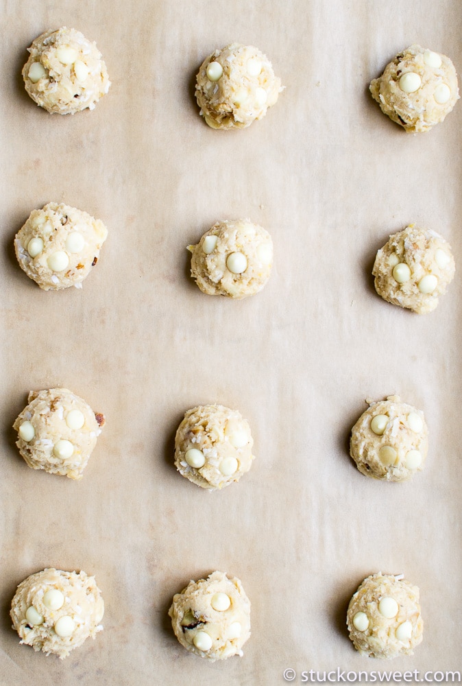 Creamy white chocolate chip cookie dough balls prepared for baking on parchment paper, ready to be dipped in chocolate or served as cookie dough treats. Perfect for homemade desserts and sweet snack recipes.