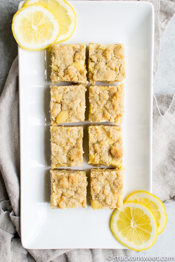 The lemon bars arranged on a plate with some lemon slices for garnish.