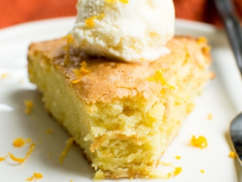 Fluffy lemon sheet cake topped with vanilla ice cream and lemon zest, served on a white plate. Perfect for lemon dessert lovers and moist cake enthusiasts.