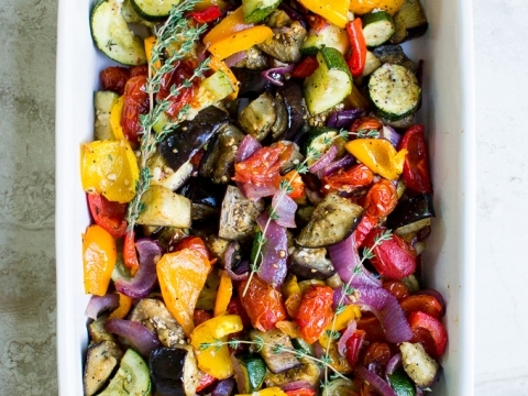 Colorful roasted vegetable medley in a white baking dish, including zucchini, eggplant, cherry tomatoes, red onion, and bell peppers, perfect for healthy eating and meal prep.